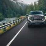 Gray 2019 GMC Sierra 1500 driving towards camera on mountain woodland road