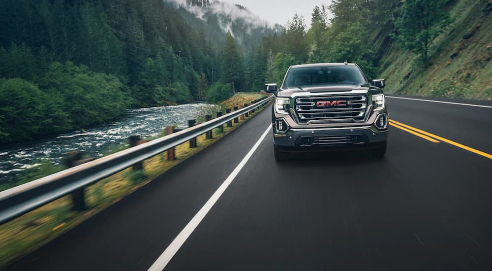 Gray 2019 GMC Sierra 1500 driving towards camera on mountain woodland road