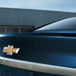 Dark blue 2019 Chevy Impala rear end, closeup of name/logo, garage door in back