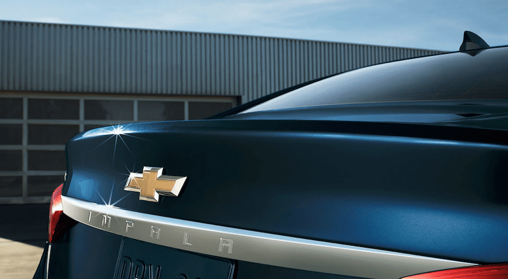 Dark blue 2019 Chevy Impala rear end, closeup of name/logo, garage door in back