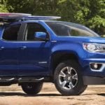 A blue Chevy Colorado with a surf board on the roof