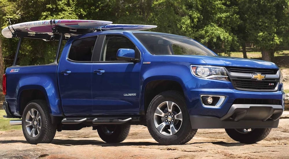 A blue Chevy Colorado with a surf board on the roof