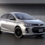 A silver 2019 Chevy Sonic sedan parked in front of a concrete building