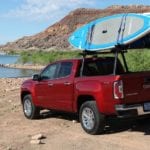 A red 2019 GMC Canyon with surfboards at a beach