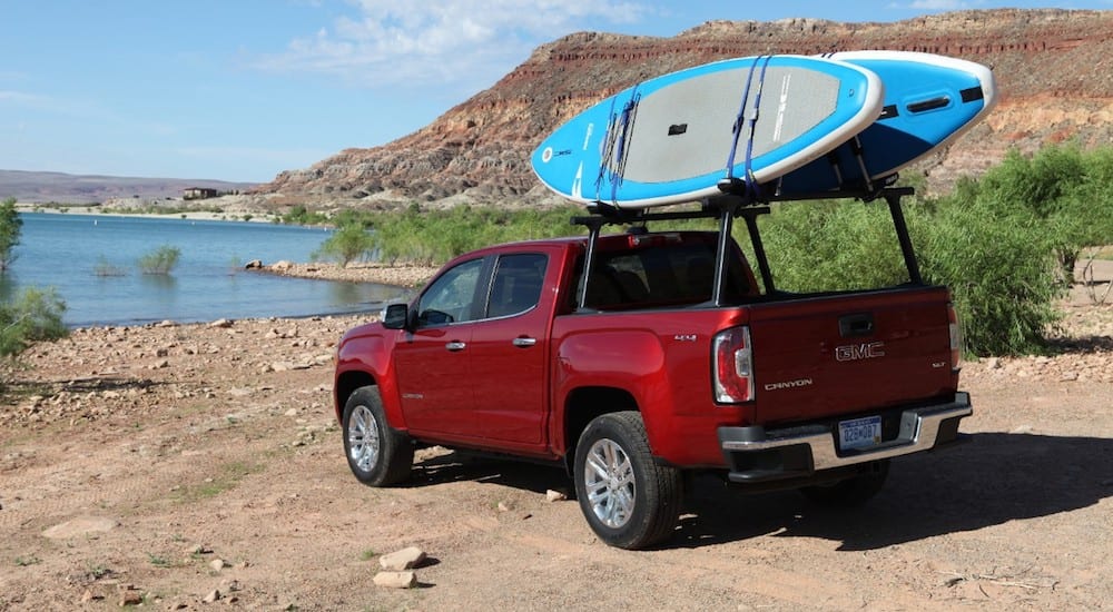 A red 2019 GMC Canyon with surfboards at a beach
