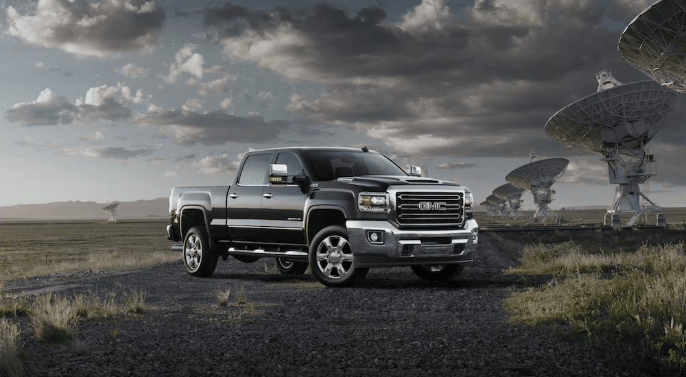 A black 2019 GMC Sierra 2500HD in a fields with giant satellite receivers