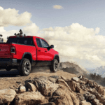A red 2019 Ram 1500 on a majestic mountain against a cloudy sky
