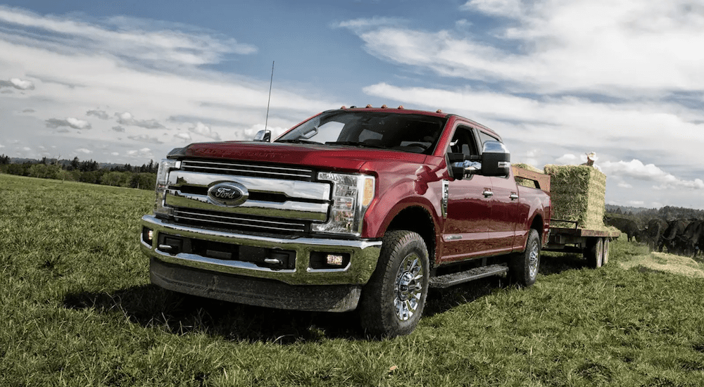 A red 2019 Ford F-250 pulls a trailer in a green field