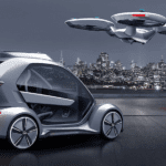 A silver Audi Pop.up.Next concept car and drone with NYC in the back at night