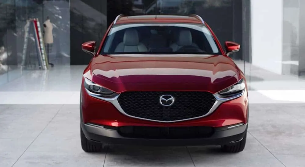 A red 2020 Mazda CX-30, which can be found at your local Mazda dealer, is parked in a white showroom.