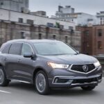 A dark gray 2017 Certified pre-owned Acura MDX travels city streets