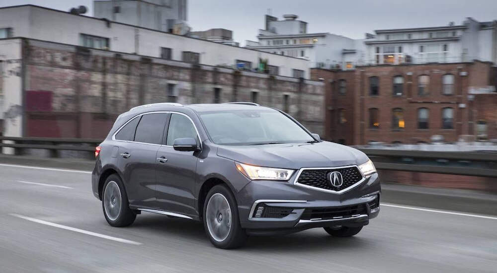 A dark gray 2017 Certified pre-owned Acura MDX travels city streets