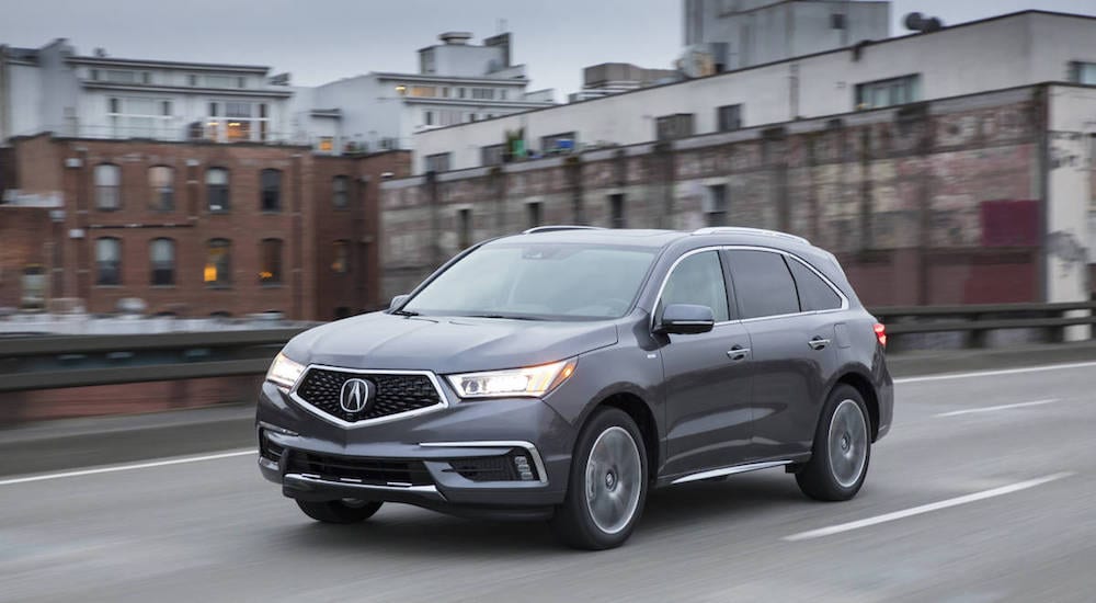 A dark gray 2017 Certified pre-owned Acura MDX travels city streets