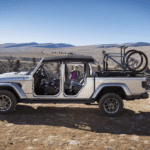 A silver 2020 Jeep Gladiator with bikes in the bed with mountains in the back