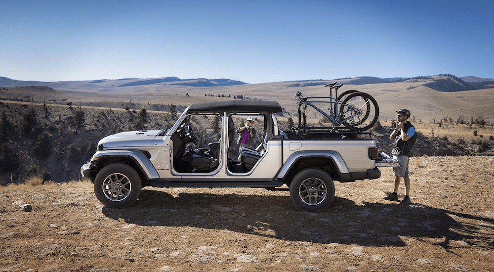 A silver 2020 Jeep Gladiator with bikes in the bed with mountains in the back