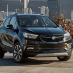 A 2019 black Bluick Encore is pictured in front of several city buildings.