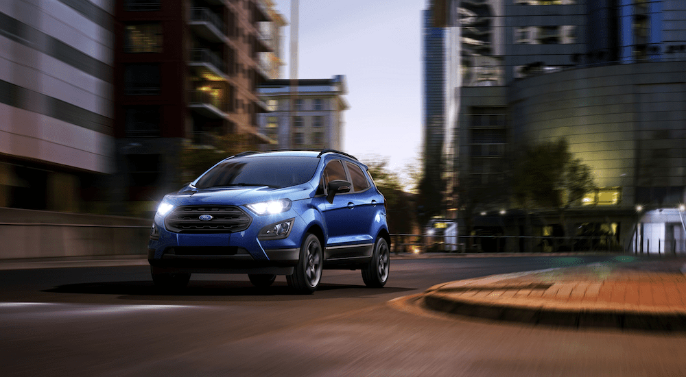 A blue 2019 Ford Ecosport is driving in the city at dusk.