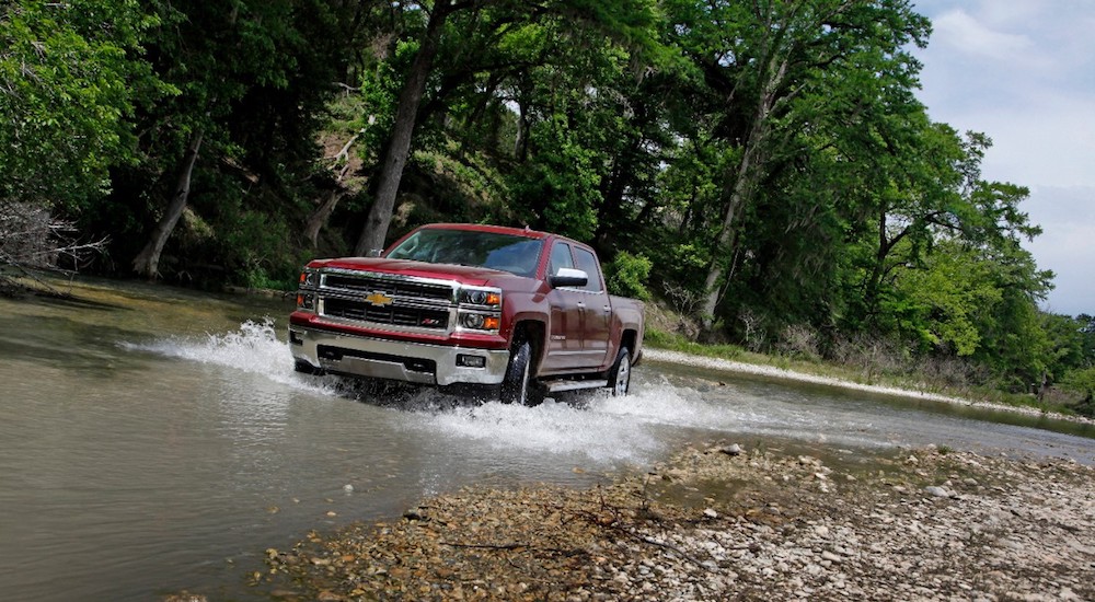 A red 2015 Chevy Silverado driving through a river