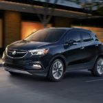 A black 2019 Buick Encore is driving at a darker hour.