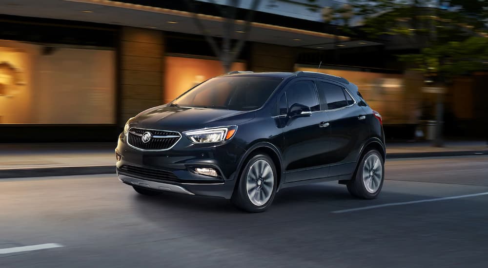 A black 2019 Buick Encore is driving at a darker hour.