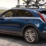 A blue 2019 Cadillac XT4 is parked with bikes on the top and a view.