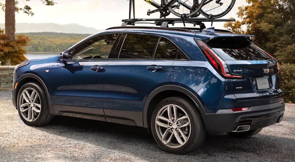 A blue 2019 Cadillac XT4 is parked with bikes on the top and a view.