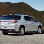 A silver 2019 Chevy Traverse is parked on a gravel driveway facing hills.