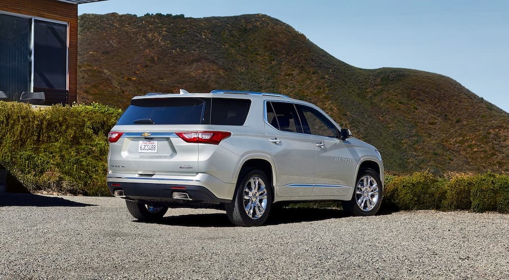 A silver 2019 Chevy Traverse is parked on a gravel driveway facing hills.