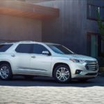 A white 2019 Chevy Traverse is parked outside a modern house.