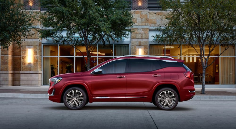 A red 2019 GMC Terrain Denali is parked in front of shops.