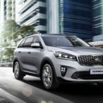 A silver 2019 KIA Sorento is driving through the city.