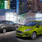 A green 2019 Ford Fiesta is parked next to a grey one facing the opposite direction. The Fiesta is included in Ford's new strategy in this weekly automotive news segment.