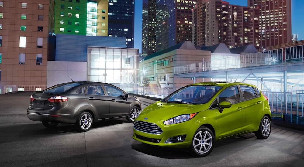 A green 2019 Ford Fiesta is parked next to a grey one facing the opposite direction. The Fiesta is included in Ford's new strategy in this weekly automotive news segment.