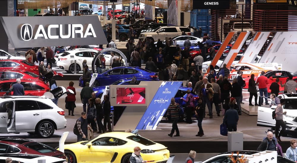 The image shows people looking at vehicles featured at the CAS, which is the main part of this weekly automotive news segment.