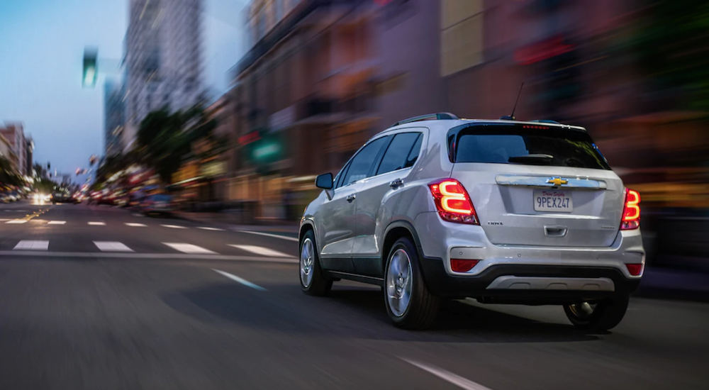 A white 2019 Chevy Trax is driving through the city at dusk.