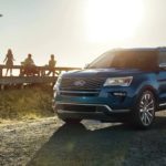 a 2019 blue Ford Explorer is parked outside a beach house while the family is on the deck.