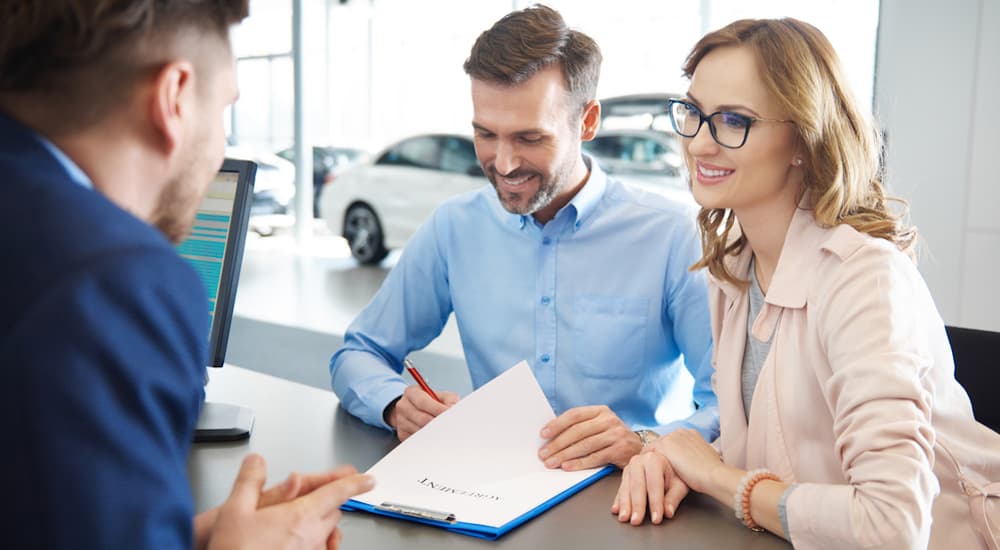 A couple is signing paperwork at a Buy Here Pay Here dealership.