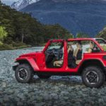 A red 2019 Jeep Wrangler, a great option for a Jeep lease deal, is parked on rocks in front of a mountain.
