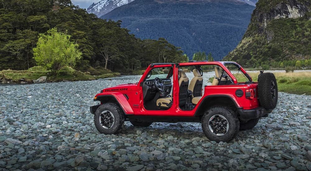 A red 2019 Jeep Wrangler, a great option for a Jeep lease deal, is parked on rocks in front of a mountain.