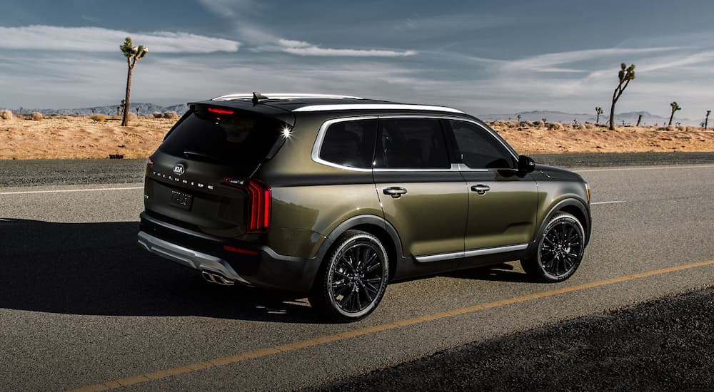 A green 2020 Kia Telluride is is driving away on a desert road.