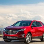 The 2019 Chevy Equinox is parked in a parking lot with a cloudy blue sky behind it.