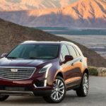 A maroon 2019 Cadillac XT5 with mountains and fields in the background.
