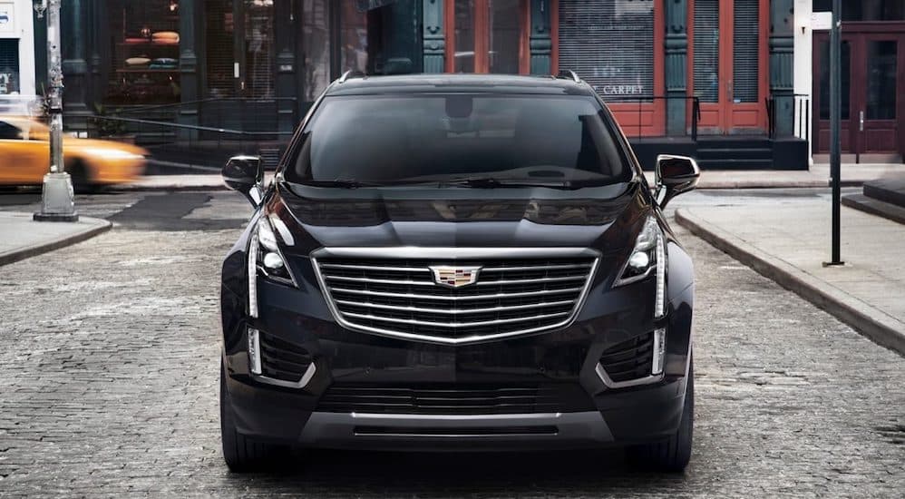 The front of a black XT5 parked on a small city street with buildings in the background. 