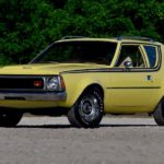 A yellow 1970 AMC Gremlin is parked in an open area.