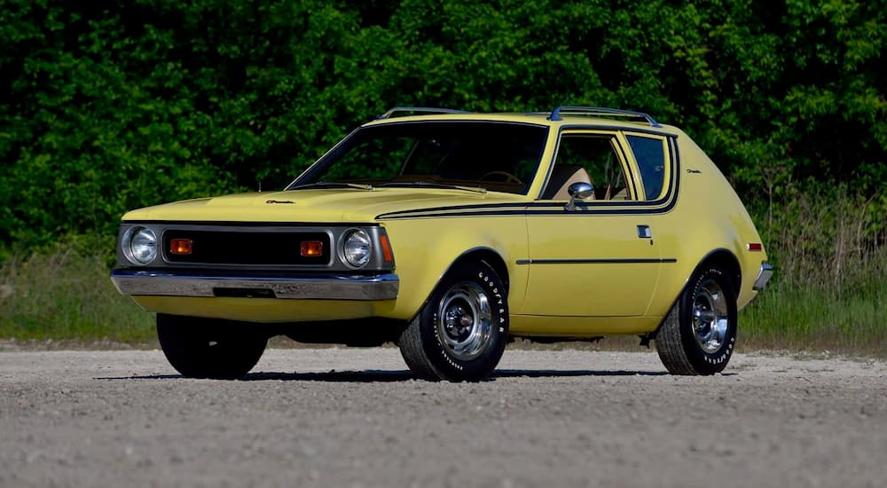 A yellow 1970 AMC Gremlin is parked in an open area.