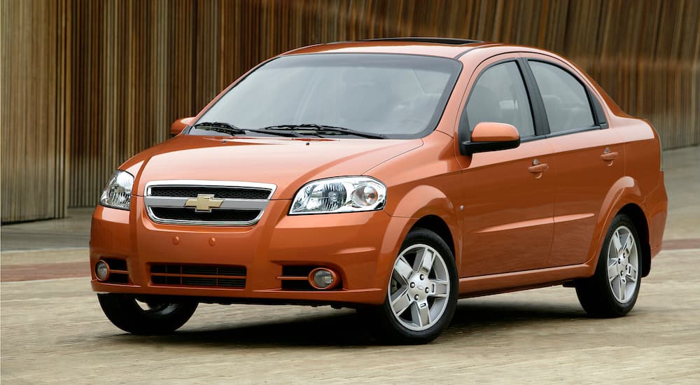 An orange 2009 Chevy Aveo, one of the used cars no longer produced, is parked.