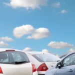 Several used cars are shown with clouds and blue sky above.
