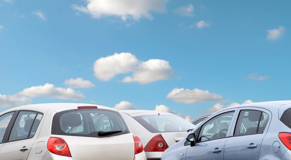 Several used cars are shown with clouds and blue sky above.