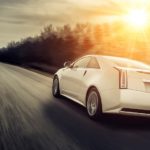 A white Cadillac driving fast down a highway