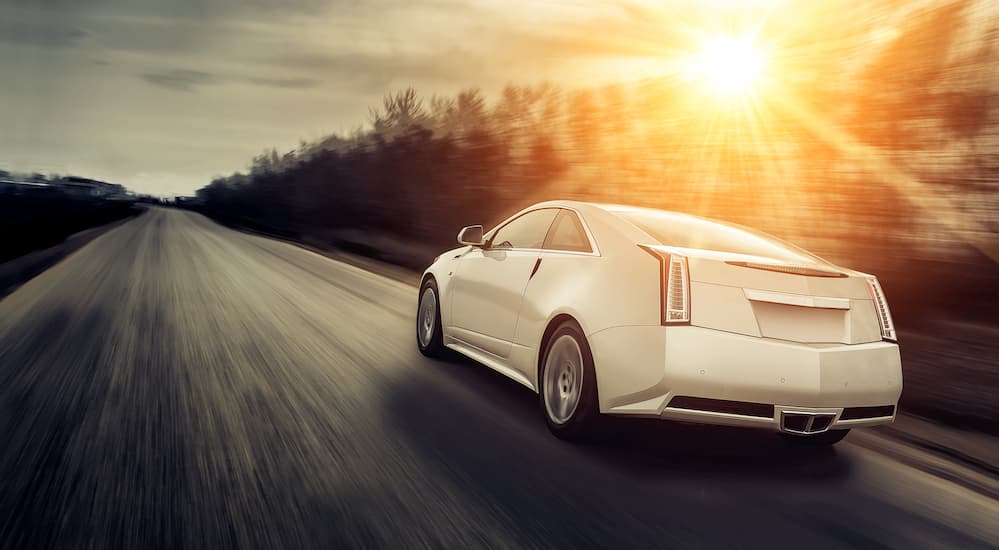 A white Cadillac driving fast down a highway